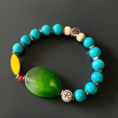 The Green Agate Summer Vibe Bracelet is a stunning accessory that exudes a sense of energy and vitality. The Green Agate stone is said to promote balance and harmony, while the other stones and beads are thought to have their own unique energy properties as well.The bracelet also features a vibrant yellow African bead, which is said to symbolize happiness and prosperity. Together, these elements create a beautiful and vibrant piece that is perfect for adding a touch of color to any summer outfit Agate Bracelets With Natural Stones For Meditation, Holistic Turquoise Beaded Bracelets With Natural Stones, Agate Stretch Bracelet For Meditation, Turquoise Agate Beaded Bracelets For Healing, Turquoise Agate Bracelet With Natural Stones, Turquoise Agate Gemstone Beads Bracelet, Agate Bracelets With Polished Beads For Meditation, Handmade Turquoise Agate Bracelets, Blue Jade Beaded Bracelets For Healing