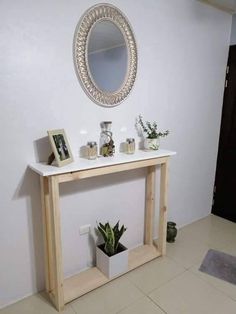 a white table with some plants on it and a mirror hanging above the table in front of it