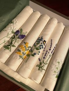 six embroidered napkins in a box with flowers on them