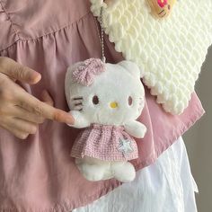 a hello kitty keychain is being held by a woman in a pink dress