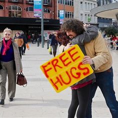 a man hugging a woman while holding a free hugs sign