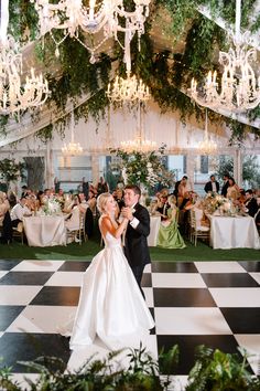 a bride and groom share their first dance at the wedding reception with chandeliers hanging from the ceiling