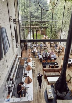 an overhead view of people sitting at tables in a restaurant with large windows and lots of greenery