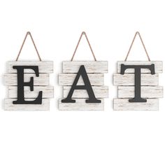 three wooden eat signs hanging from strings on a white wall with the word eat spelled in grey letters