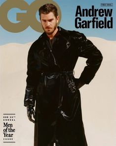 a man standing in front of a magazine cover with his hands on his hips and wearing a black coat