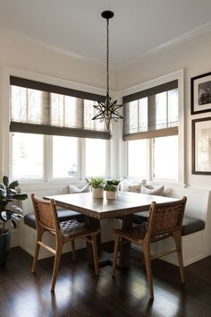 a dinning room table with chairs and a bench in front of two windows that have blinds on them