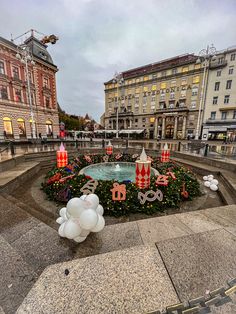 a christmas display in the middle of a city square with balloons and decorations around it