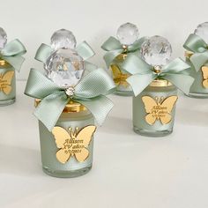 four small glass jars with bows and butterflies on them, each decorated with a gold - plated butterfly