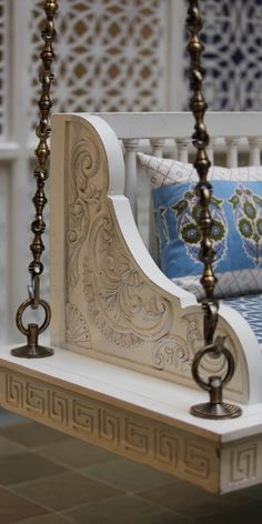 a white bed with blue and gold pillows on it's headboard is shown