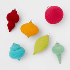 four different colored seashell ornaments on a white surface