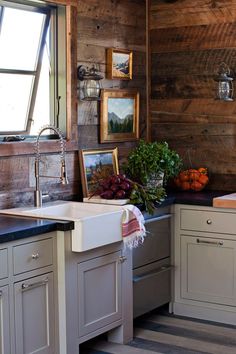 a kitchen with white cabinets and black counter tops next to a window filled with plants