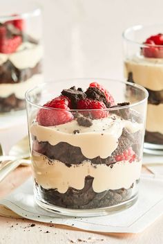 two desserts with raspberries, chocolate and cream in glass dishes on a table