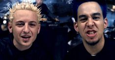 two men with spiked hair and piercings on their heads, one is making a face