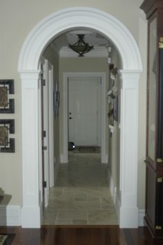 an archway leading into a living room next to a doorway with a clock on the wall