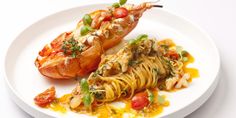 lobster and pasta dish served on white plate with tomato garnishes in center