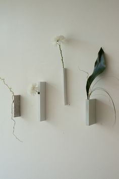 three cement vases with flowers in them hanging on the wall