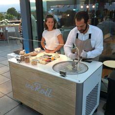 a man and woman preparing food at an ice cream stand