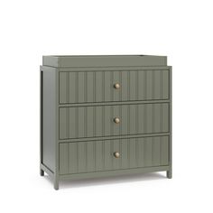 a grey dresser with three drawers and two brass knobs on the front, against a white background