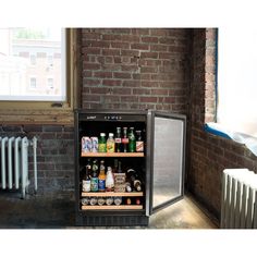 an empty mini fridge is shown in front of a brick wall and radiator