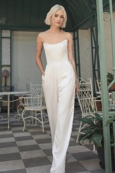 a woman standing in front of a building wearing white pants and a strapless top