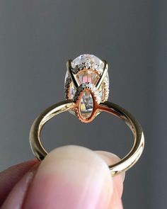 someone is holding their engagement ring with an oval shaped diamond in the center and two small diamonds on each side