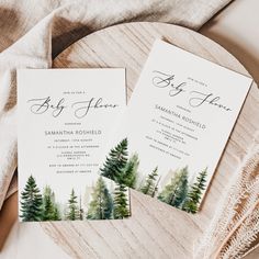 two watercolor pine trees are on top of the wedding stationery