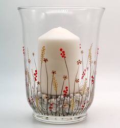 a white candle is sitting in a glass vase