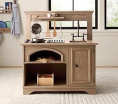 a small wooden kitchen set with an oven and sink in the center, on carpeted flooring