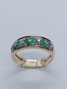 a gold ring with green and white stones