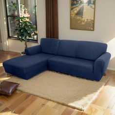 a blue couch sitting in the middle of a living room next to a rug on top of a hard wood floor