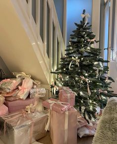 a christmas tree with presents under the stairs