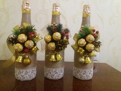 three wine bottles decorated with christmas decorations and bows on top of a wooden table in front of a wall