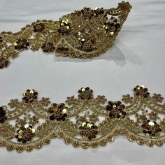 two pieces of gold sequins on a white tablecloth with black and brown beads