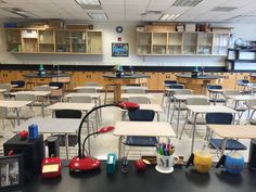 an empty classroom with desks and chairs in the middle, filled with school supplies