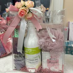 a pink gift basket filled with personal care products and flowers on top of a table