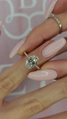 a woman's hand with pink manies and a ring on her finger, holding a diamond engagement ring