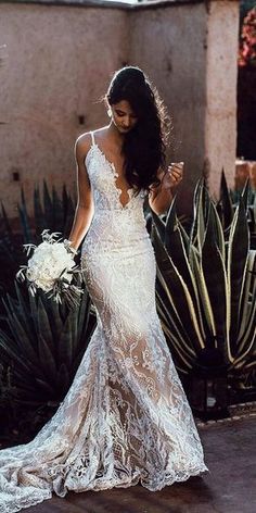 a woman in a wedding dress standing next to a cactus