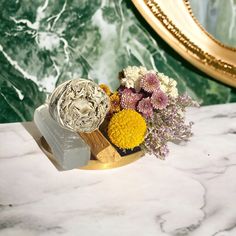 a vase filled with flowers sitting on top of a marble counter next to a mirror