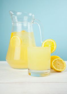 a pitcher and glass filled with lemonade sitting on a table