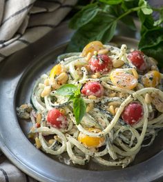 a plate of pasta with tomatoes and spinach