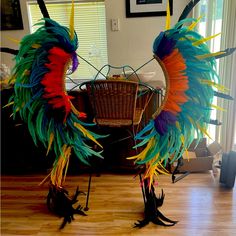 two large colorful birds standing next to each other on top of a hard wood floor