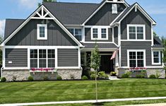 a large gray house with white trim on the windows and two flags in front of it