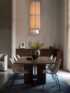 a dining room table with white chairs and a vase on the centerpiece in front of it