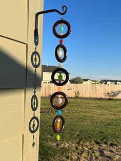 a wind chime hanging from the side of a house in front of a fence