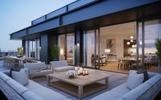 an outdoor living area with couches, tables and lamps on the roof terrace at dusk