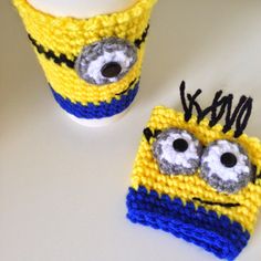 two crocheted mug cozies made to look like minion faces