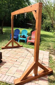 a wooden frame sitting on top of a brick patio next to two chairs and a fire pit