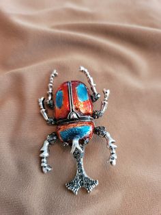 Red and blue enameled scarab brooch set in sterling silver. Multicolor Cabochon Brooches As Gift, Multicolor Cabochon Brooches For Gifts, Multicolor Cabochon Brooch As Gift, Multicolor Cabochon Brooch For Gift, Multicolor Cabochon Brooches For Collectors, Red Enamel Brooches As Gift, Red Enamel Brooch For Gift, Unique Multicolor Cabochon Brooches, Costume Jewelry Metal Brooches For Gifts