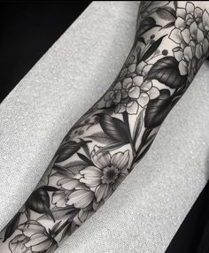 a black and white tattoo with flowers on the arm, done by an artist in his studio