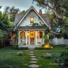 a small white house in the middle of a yard with stepping stones leading up to it's front door